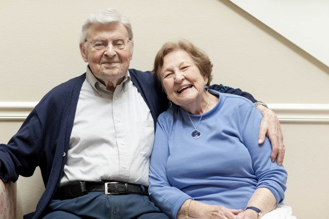 man with arm around woman sitting and smiling